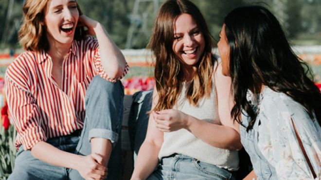 Three young women in an open field of flowers