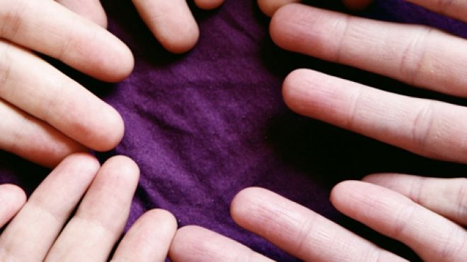 open hands in a circle on a purple cloth