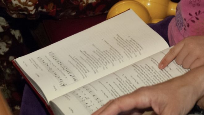 hymn book in hands of a child and adult in a pew