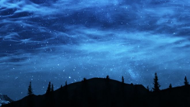 starry sky with low mountians and trees in silhouette