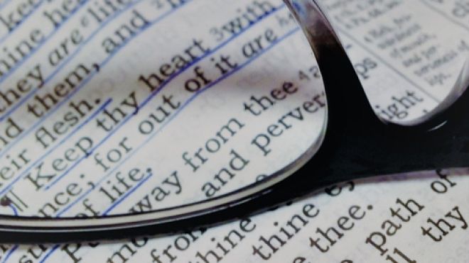 Black eyeglasses resting on a open Bible