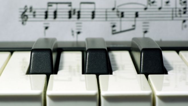 Photo of piano keys with sheet music in the background