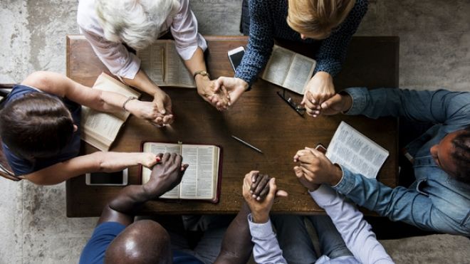 Group of diverse group of people holding hands and praying