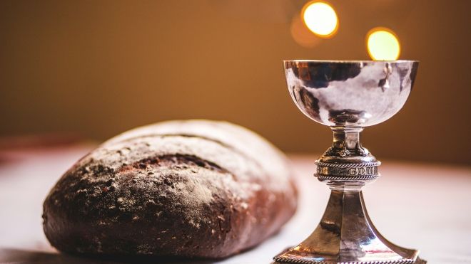 A rustic loaf and a silver cup on a white table
