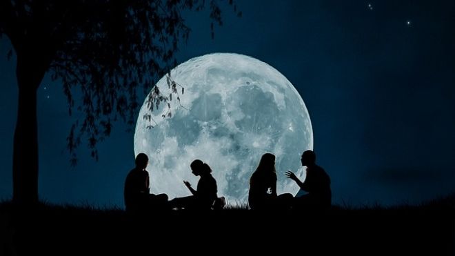 silhouettes against a large bright moon