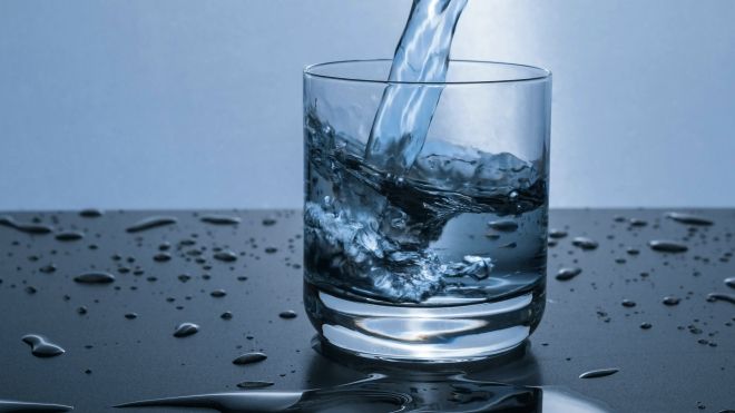 a clear glass being filled with water, blue and grey