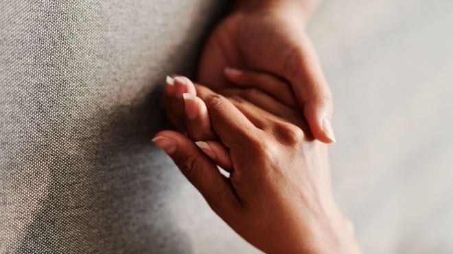 two hands holding each other on a grey background