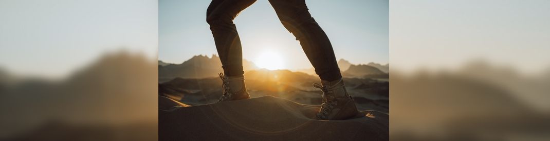 Feet walking in the desert wilderness Feet walking in the desert wilderness with sun cresting the horizon