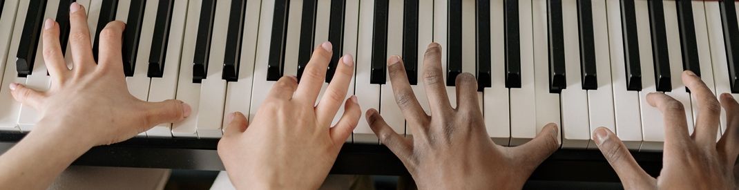 hands on piano keys Two sets of hands on piano keys