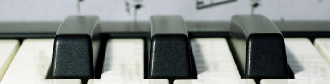 Photo of piano keys with sheet music in the background