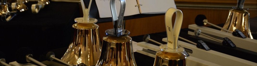 Three handbells on a table with music score in the backgroung Three handbells on a table with music score in the backgroung