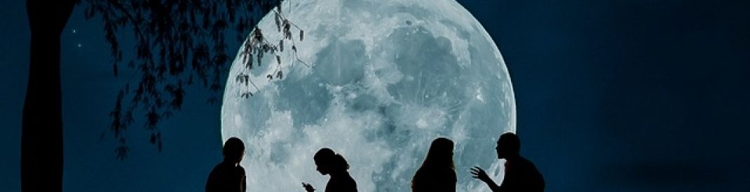 silhouettes against a large bright moon