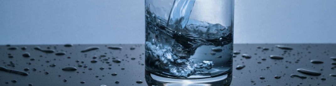 a clear glass being filled with water, blue and grey