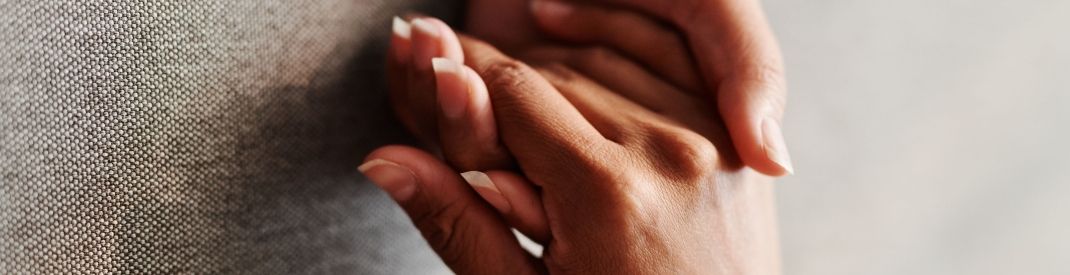 two hands holding each other on a grey background